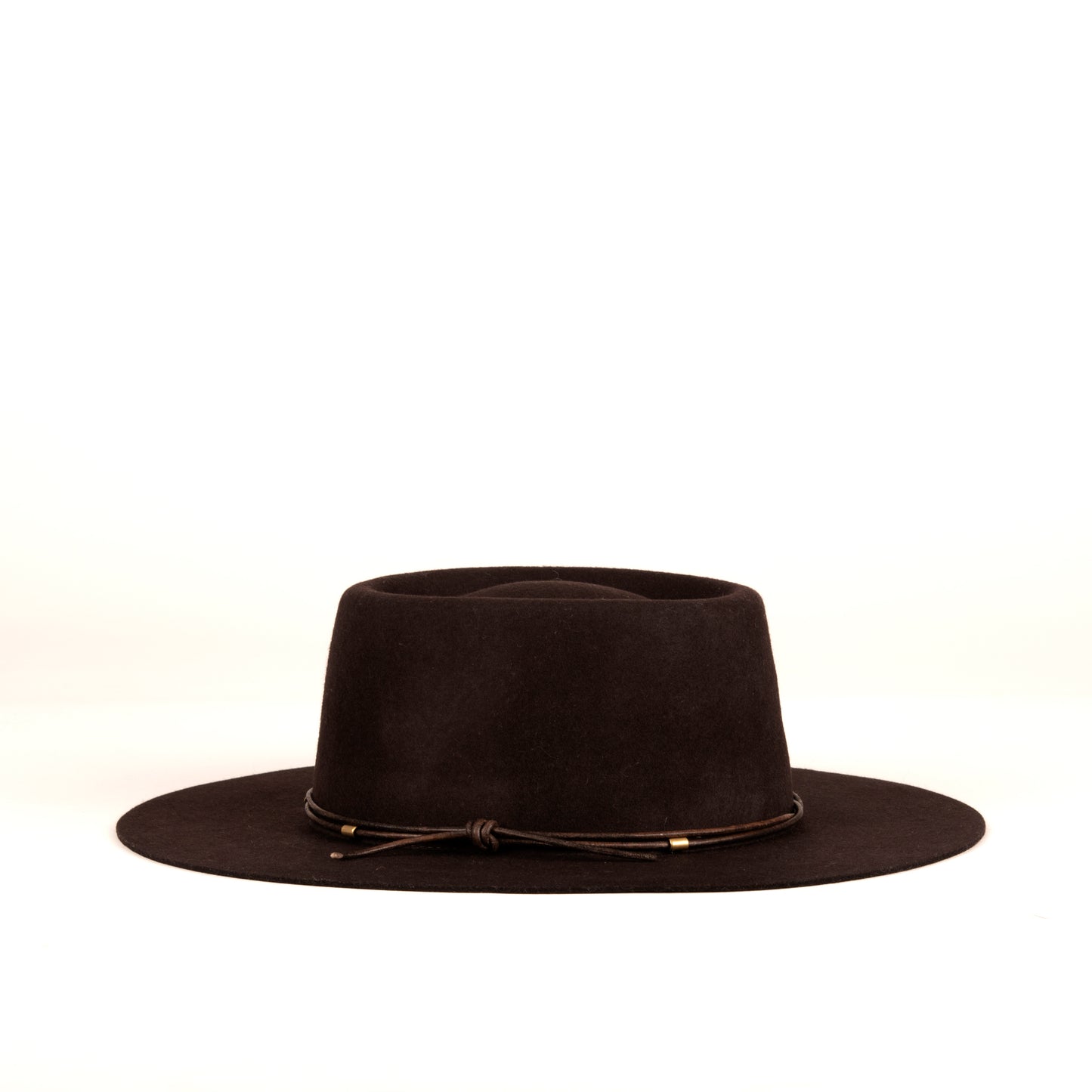 Elliot is a classic shape fedora with a telescope crown. Made of 100% dark brown wool with a leather cord detail with brass tubular bead details.
