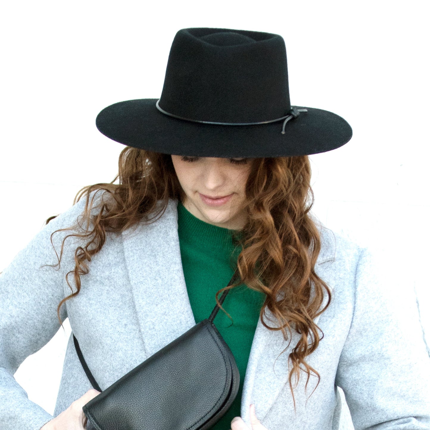 woman with brown hair wearing a black hat and grey coat