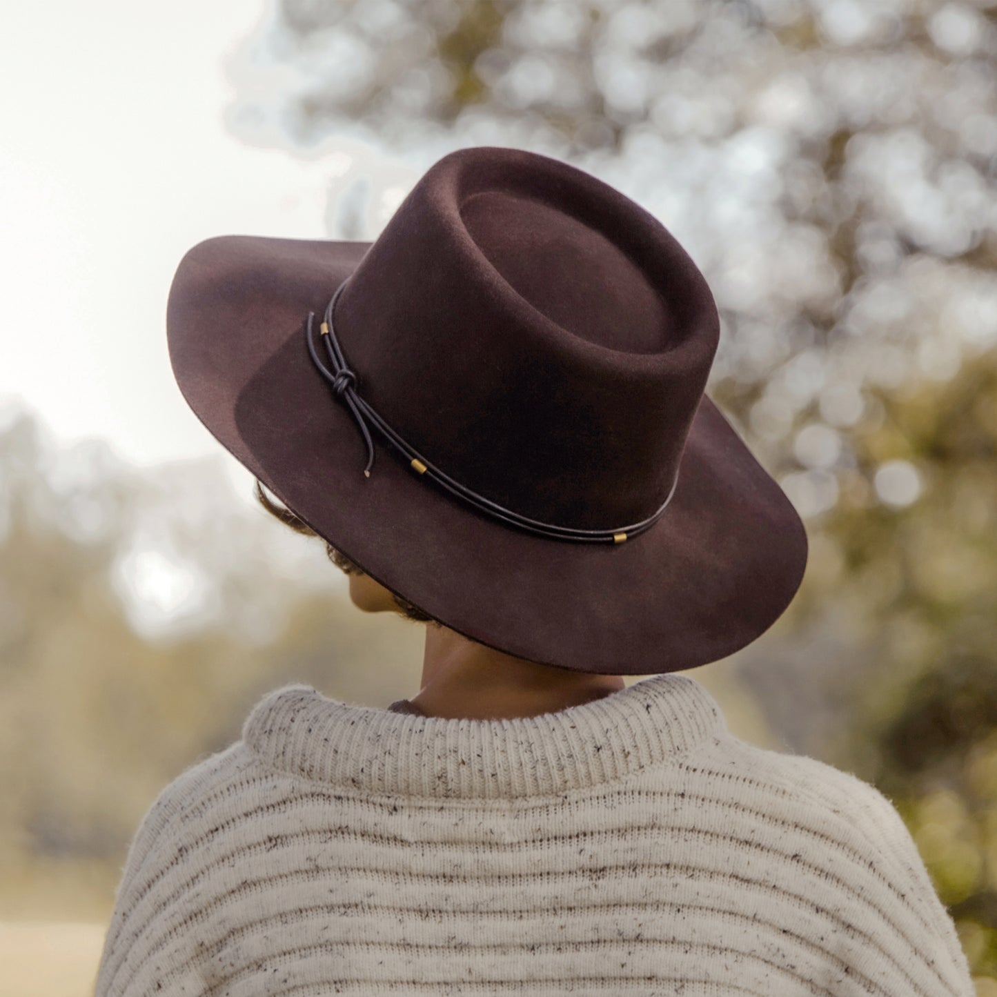 Woman in a brown wool hat stood in an autumn field